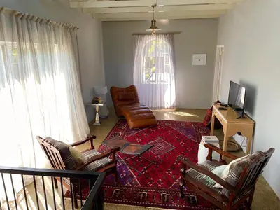 a living room with a couch and chairs and a television at The Lion Mansion - on Solar live and work anywhere in Pretoria