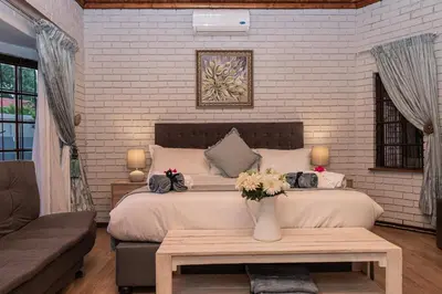 a bedroom with a bed with a vase of flowers on a table at Mereke Manor in Centurion