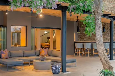 a patio with a couch and a bar with stools at Luxury Villa looking onto Kruger National Park in Belfast