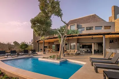 a house with a swimming pool in front of a house at Luxury Villa looking onto Kruger National Park in Belfast
