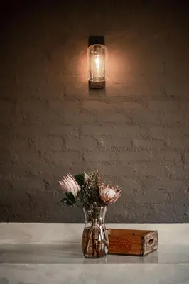 a vase with flowers sitting on a table with a light at Linvale Country Lodge in Hazyview