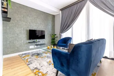 a living room with two blue chairs and a television at Alimama Spaces: The Manson Newton Villa Ellipse in Midrand