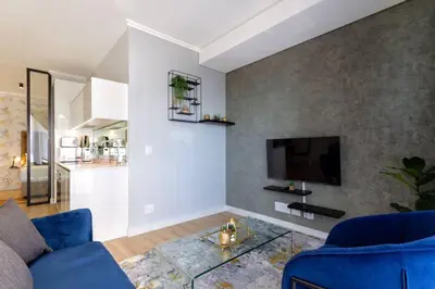 a living room with a blue couch and a tv at Alimama Spaces: The Manson Newton Villa Ellipse in Midrand