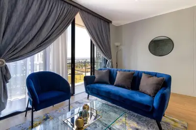 a blue couch and two chairs in a living room at Alimama Spaces: The Manson Newton Villa Ellipse in Midrand