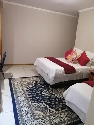 a hotel room with two beds and a rug at ROYAL LODGE in Witbank