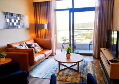 a living room with a couch and a table and a tv at Menlyn Apartment - Trilogy in Pretoria