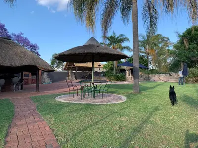 a black dog walking around a park with a table and chairs at Sunset Guesthouse and Venue Cullinan in Meule
