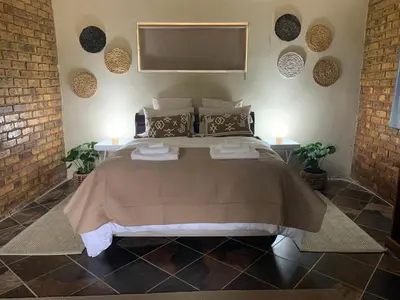 a bedroom with a large bed with two lamps at Sunset Guesthouse and Venue Cullinan in Meule