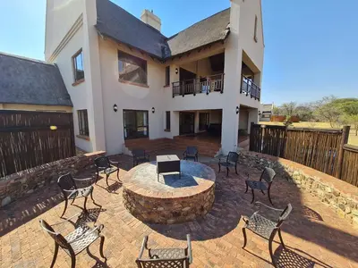 a patio with chairs and a fire pit in front of a house at Zebula No 2 Waterbergs Over the Savannah 4 Bedroom in Mabula