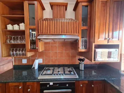 a kitchen with a stove top oven and wooden cabinets at Zebula No 2 Waterbergs Over the Savannah 4 Bedroom in Mabula
