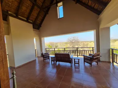 a room with chairs and a table and a large window at Zebula No 2 Waterbergs Over the Savannah 4 Bedroom in Mabula