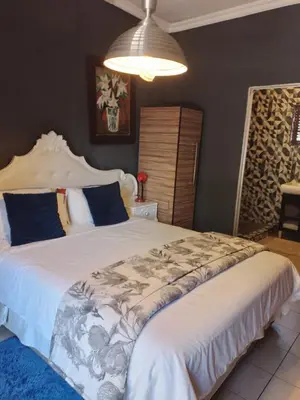 a bedroom with a large white bed with blue pillows at Aloha Menlyn Lodge Ensuite Rooms with shower all with own entrance and unlimited free WiFi in Pretoria