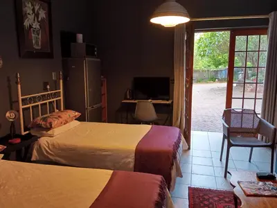 a bedroom with two beds and a sliding glass door at Aloha Menlyn Lodge Ensuite Rooms with shower all with own entrance and unlimited free WiFi in Pretoria