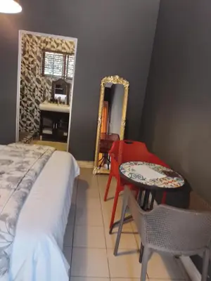 a bedroom with a bed and a table and a mirror at Aloha Menlyn Lodge Ensuite Rooms with shower all with own entrance and unlimited free WiFi in Pretoria