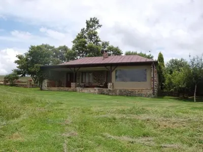 a small house in a field with a grass yard at Watersmeet cottages in Dullstroom