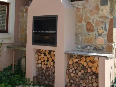 a fireplace with a pile of fire wood at Watersmeet cottages in Dullstroom