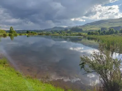 a body of water with clouds in the water at Watersmeet cottages in Dullstroom