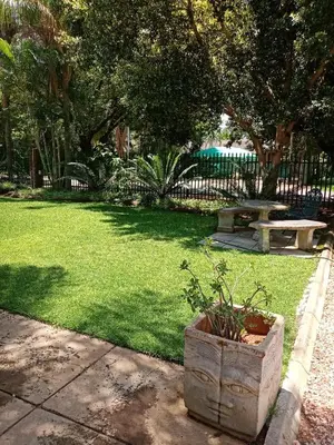 a park with a bench and a table and grass at De la Rose Guesthouse in Lephalale
