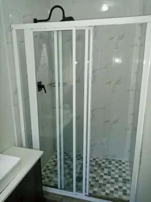 a shower with a glass door in a bathroom at De la Rose Guesthouse in Lephalale