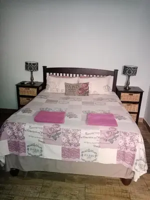 a bed with pink and white sheets and pillows at De la Rose Guesthouse in Lephalale