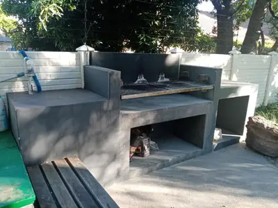 a barbecue grill with a bench in a backyard at De la Rose Guesthouse in Lephalale