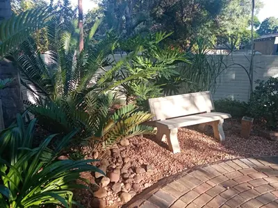 a bench sitting in the middle of a garden at De la Rose Guesthouse in Lephalale