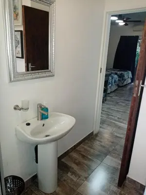 a bathroom with a sink and a mirror and a hallway at De la Rose Guesthouse in Lephalale
