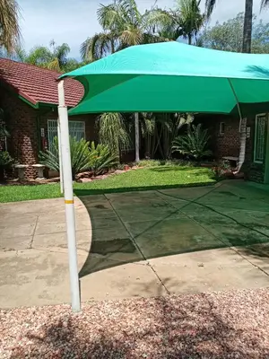 a green umbrella in front of a house at De la Rose Guesthouse in Lephalale