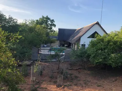 a small white house with a gambrel roof at Marloth Park, Kruger safari house - solar in Marloth Park