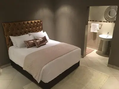 a bedroom with a bed and a bathroom with a sink at Charli’s Lodge in Mpheleng