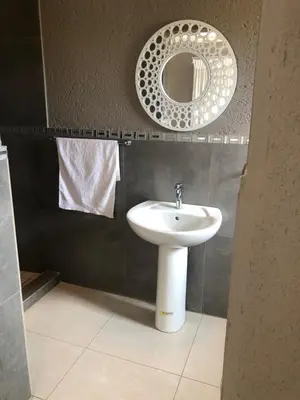 a bathroom with a sink and a mirror at Charli’s Lodge in Mpheleng