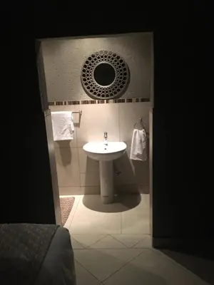 a bathroom with a sink and a mirror at Charli’s Lodge in Mpheleng