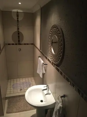 a bathroom with a sink and a shower with a mirror at Charli’s Lodge in Mpheleng