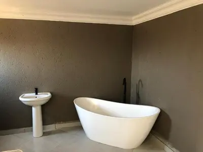 a bathroom with a white bath tub next to a sink at Charli’s Lodge in Mpheleng
