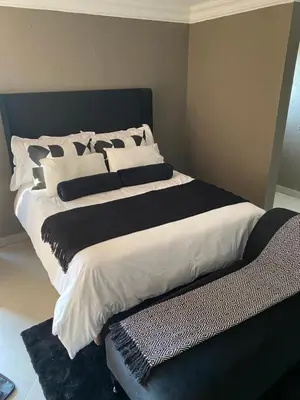 a large bed with black and white sheets and pillows at Charli’s Lodge in Mpheleng