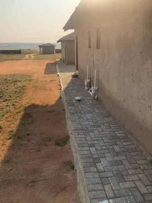 a brick walkway next to a building in a field at Charli’s Lodge in Mpheleng