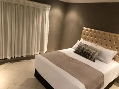 a bedroom with a large bed with white sheets and pillows at Charli’s Lodge in Mpheleng