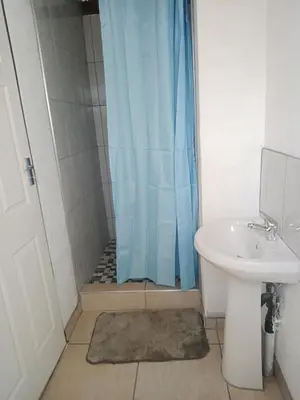 a shower with a blue shower curtain next to a sink at PARK FRONT LODGE in Polokwane