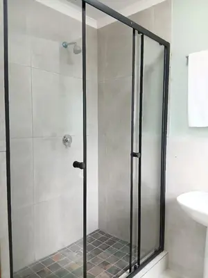 a shower with a glass door in a bathroom at Bossi Lodge in Hartbeespoort