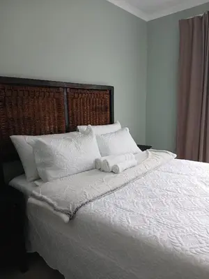 a white bed with two rolled towels on it at Bossi Lodge in Hartbeespoort