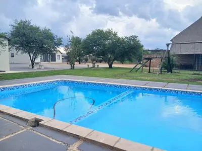 a large blue swimming pool with a playground at Bossi Lodge in Hartbeespoort