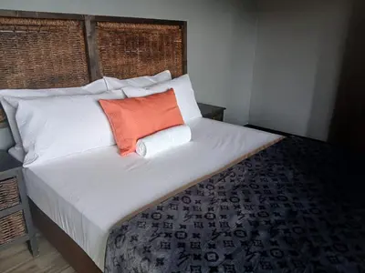 a bed with two pillows and an orange pillow on it at Bossi Lodge in Hartbeespoort