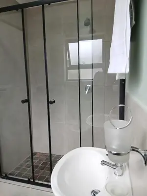 a bathroom with a shower and a toilet and a sink at Bossi Lodge in Hartbeespoort