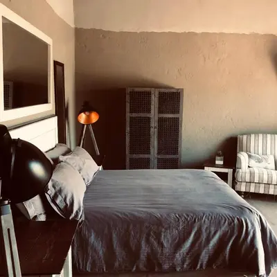 a bedroom with a bed and a lamp and a chair at Simba Safaris African Pride Exotic Lodge in Lephalale