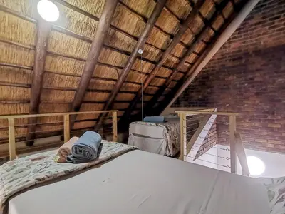 a attic room with a bed and a brick wall at Athule Inn Marloth - Units in Marloth Park
