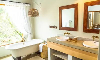 a bathroom with two sinks and a tub and a mirror at Eclectic Safari Lodge in Mabula