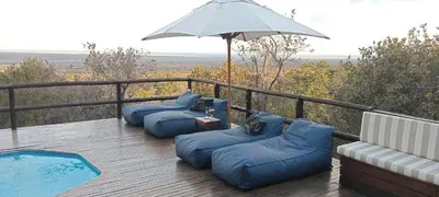 a deck with two blue bean bags and an umbrella at Eclectic Safari Lodge in Mabula