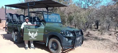 a man is standing next to a green jeep at Eclectic Safari Lodge in Mabula