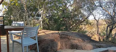 a blue chair sitting next to a table and a rock at Eclectic Safari Lodge in Mabula