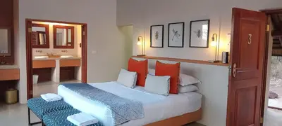 a bedroom with a bed with orange and blue pillows at Eclectic Safari Lodge in Mabula